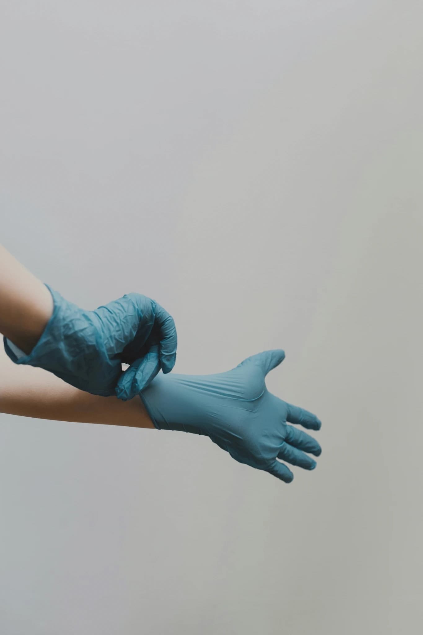 Hands pulling on blue medical gloves